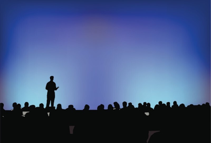 person speaking in front of crowd at an auction