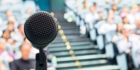 closeup of microphone with blurred crowd in background