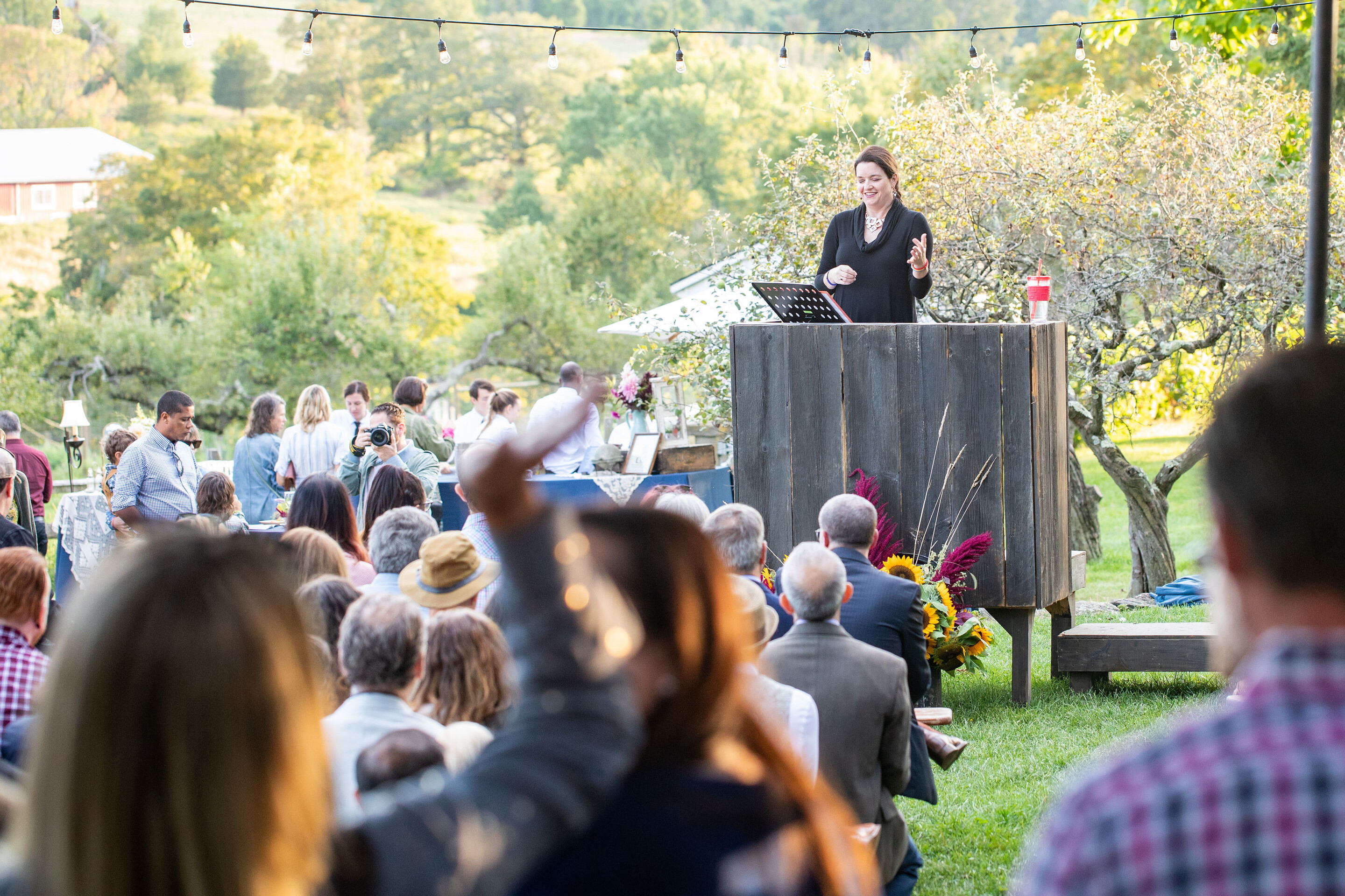 woman auctioneer at a fundraising event in a apple orchard raiaing funds for a nonprofit